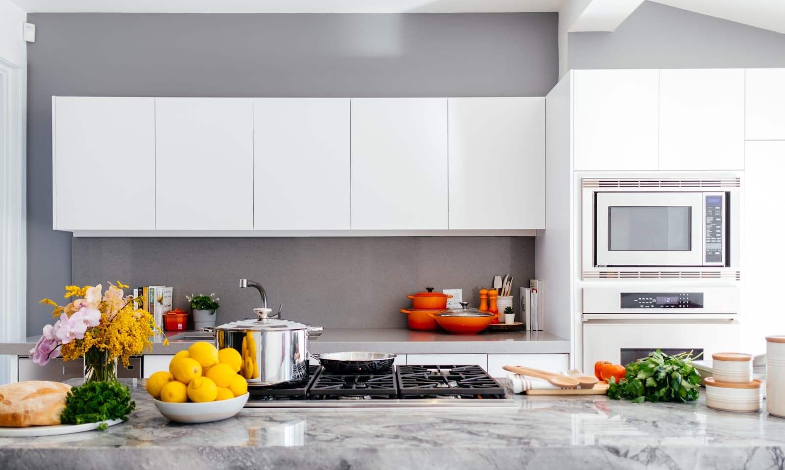 Bright modern kitchen with marble island, white cabinetry, and under-cabinet lighting